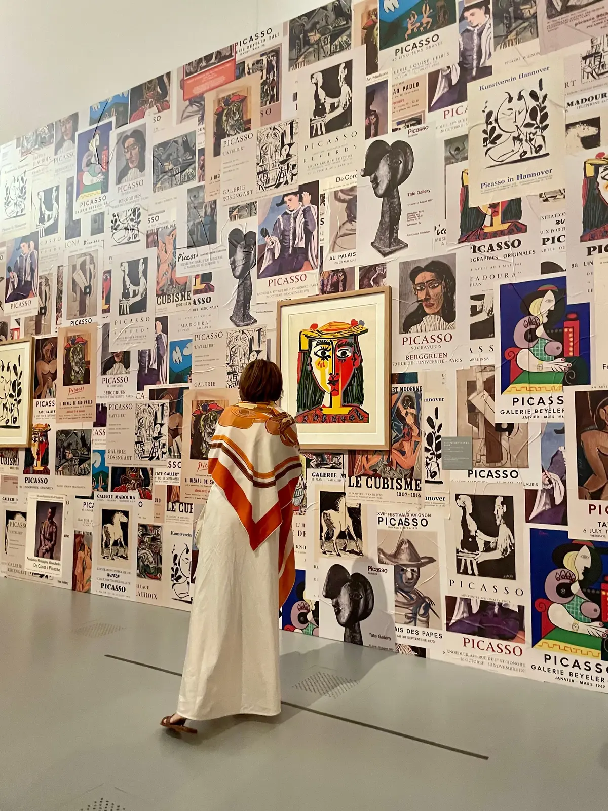 ピカソのポスターが壁に密集して並び、観客が絵画を鑑賞している