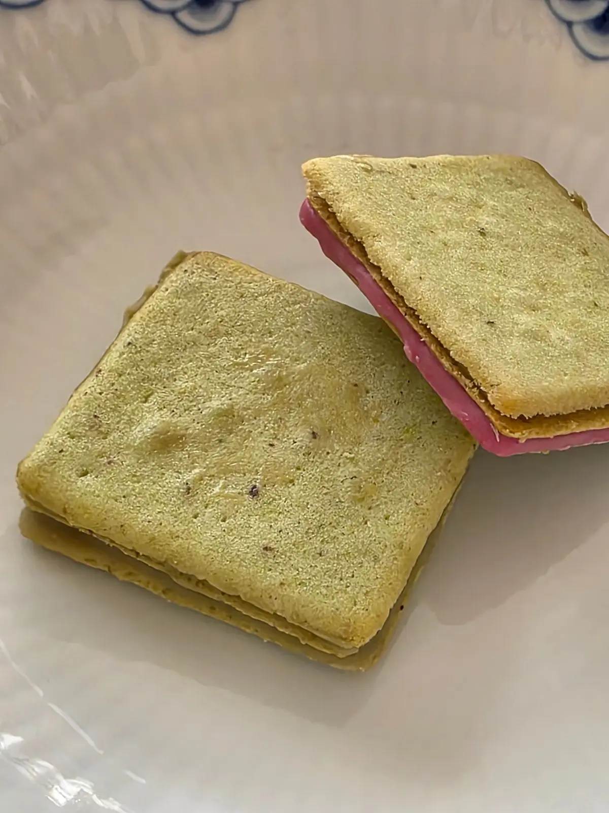 緑色のクッキーで挟まれたピンク色のクリームが詰まったお菓子。2つ並んでおり、1つは斜めに置かれている。