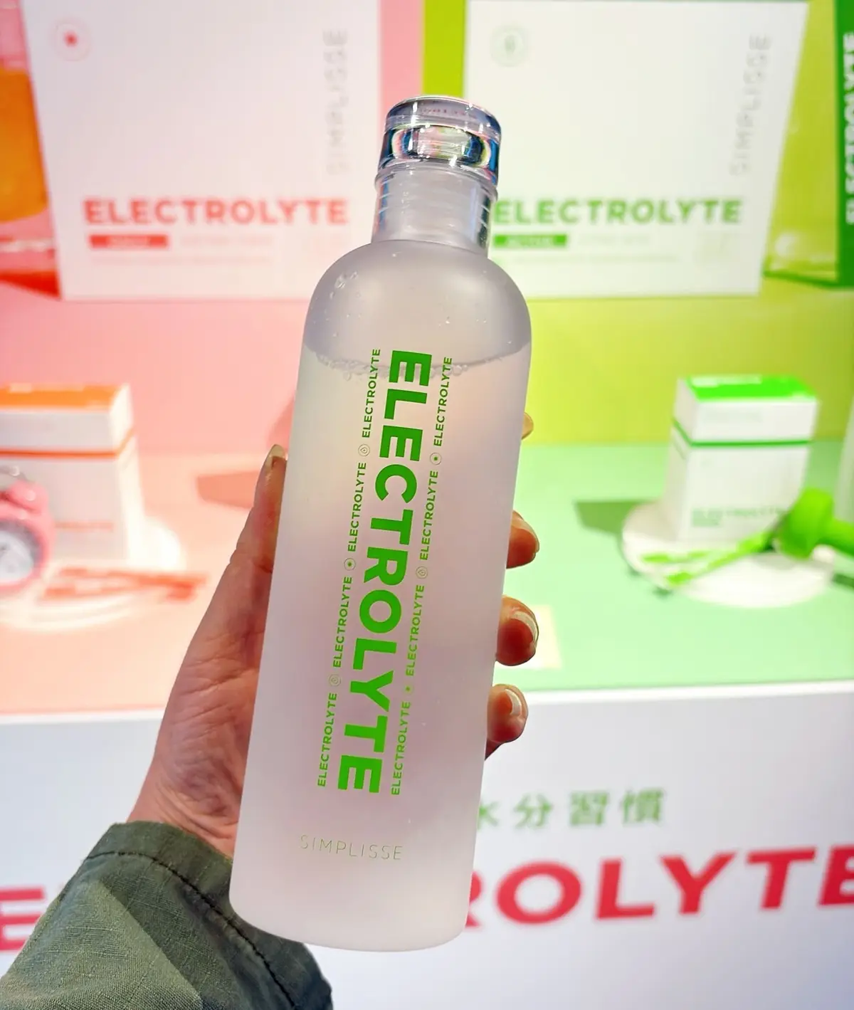シンプリス　新作コスメ　インナーケア　エイジングケア　白いボトルに緑色の文字で「ELECTROLYTE」と書かれた電解質飲料を手に持つ人