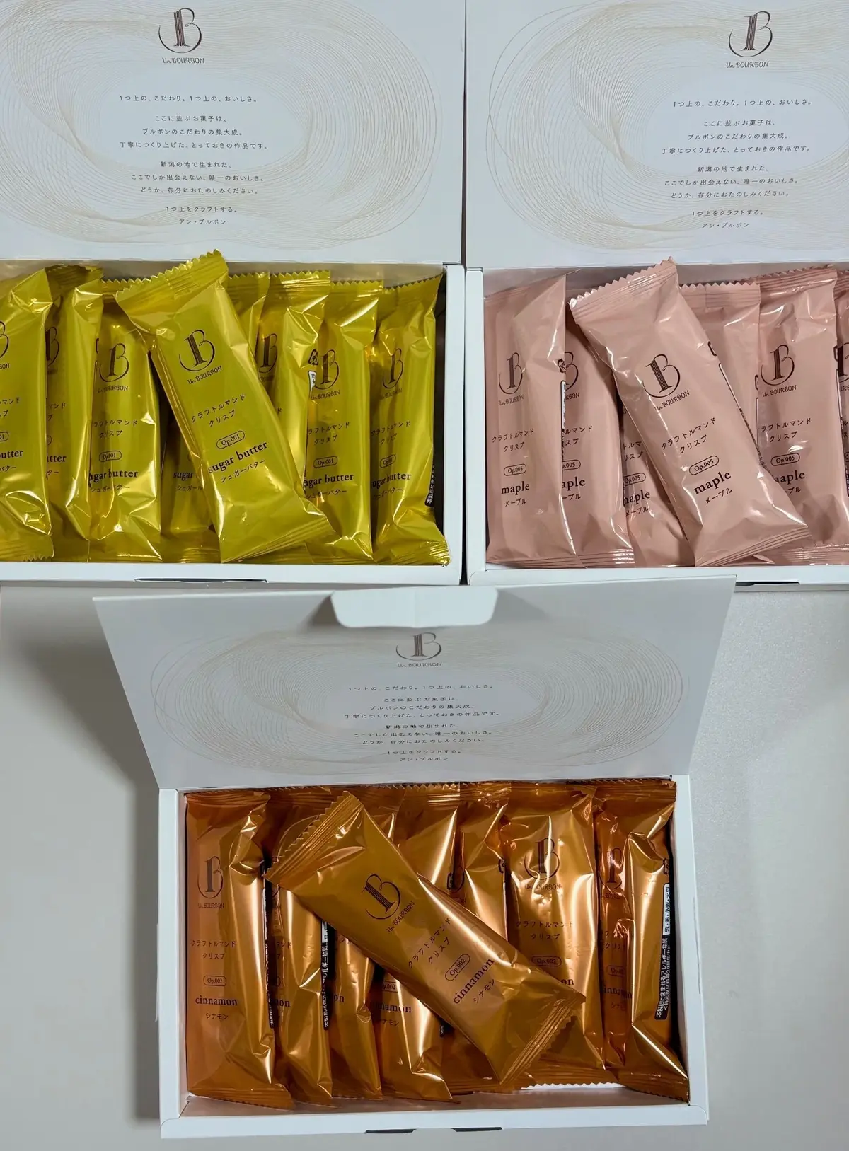 Le Bon Bon Bonbonのチョコレートが、3種類のフレーバー（シュガーバター、メープル、シナモン）で整然と並んでいる様子。それぞれ、ゴールドとピンクを基調としたパッケージが特徴。