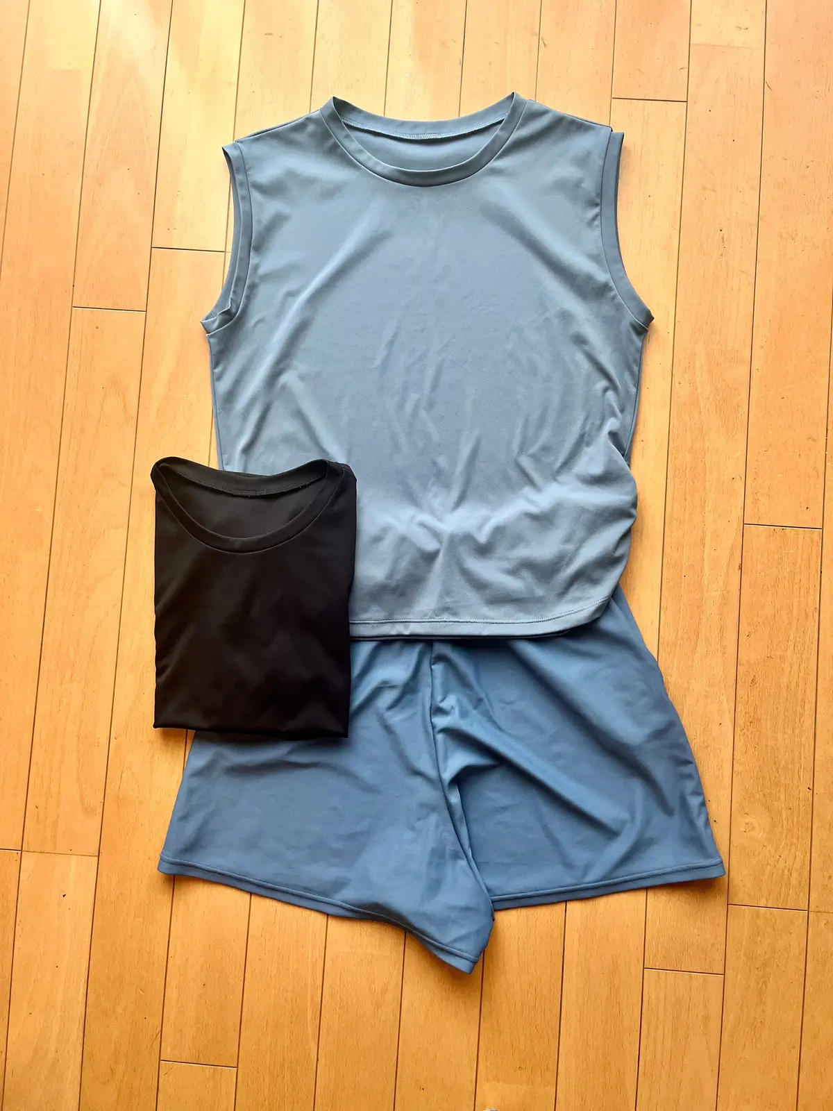 床に、青色のタンクトップとショートパンツ、黒色のTシャツが置かれている。