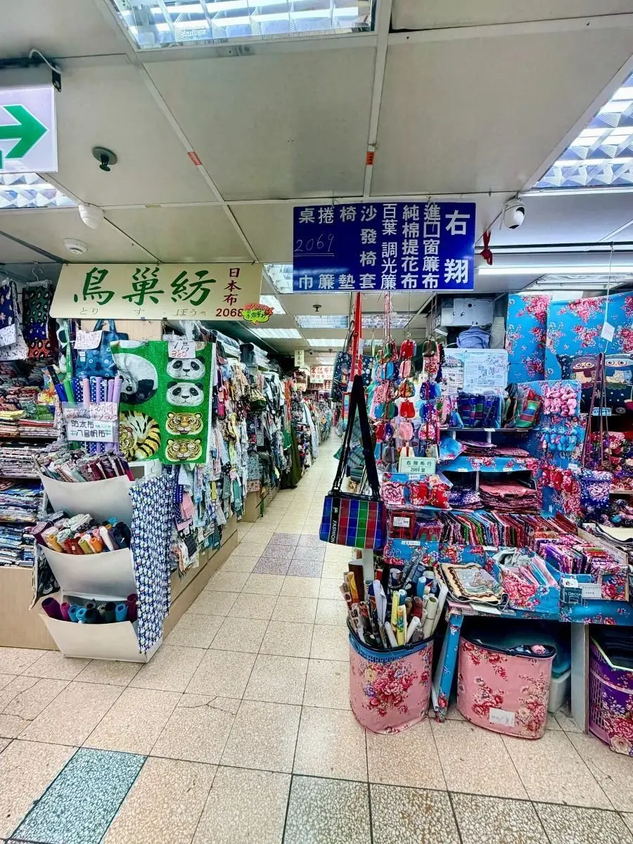 手芸用品が並ぶ店内。棚に布地や糸が色鮮やかに並び、ポーチや小物も展示されている。