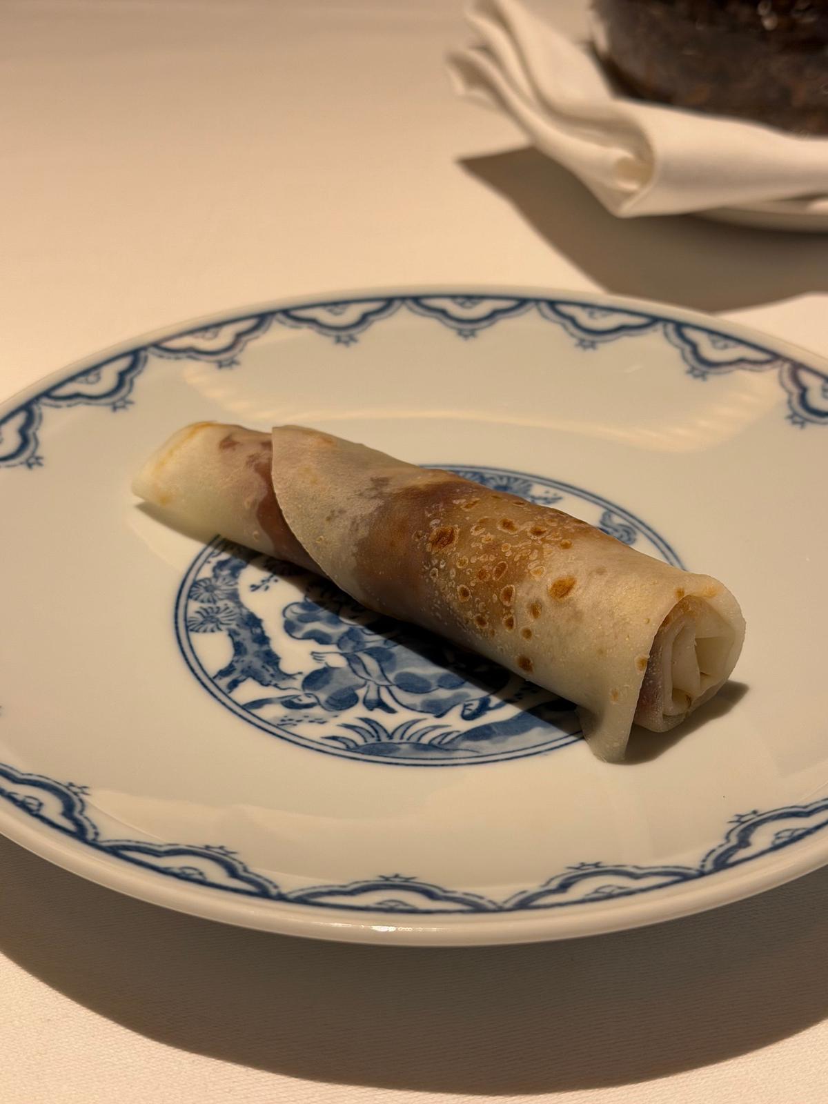 青と白の装飾が施されたプレートに、茶色い表面のクレープが1つ置かれている