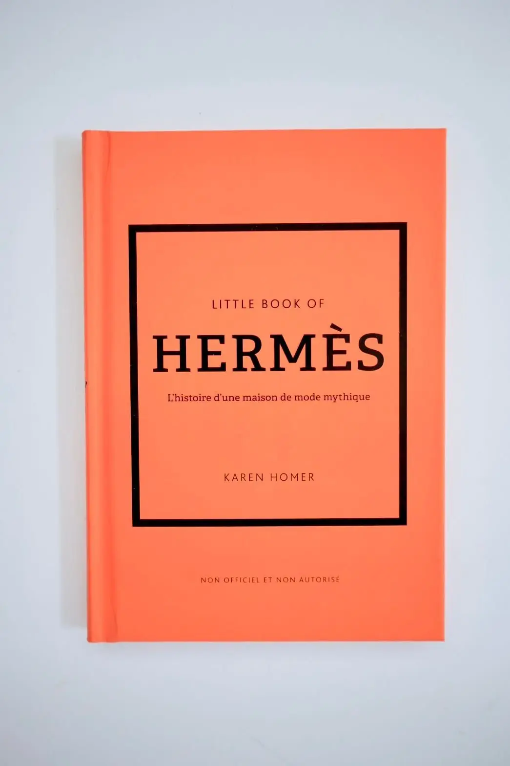 エルメスの本。オレンジ色の表紙に黒い枠で「Little Book of Hermès」と白文字で表記された本。