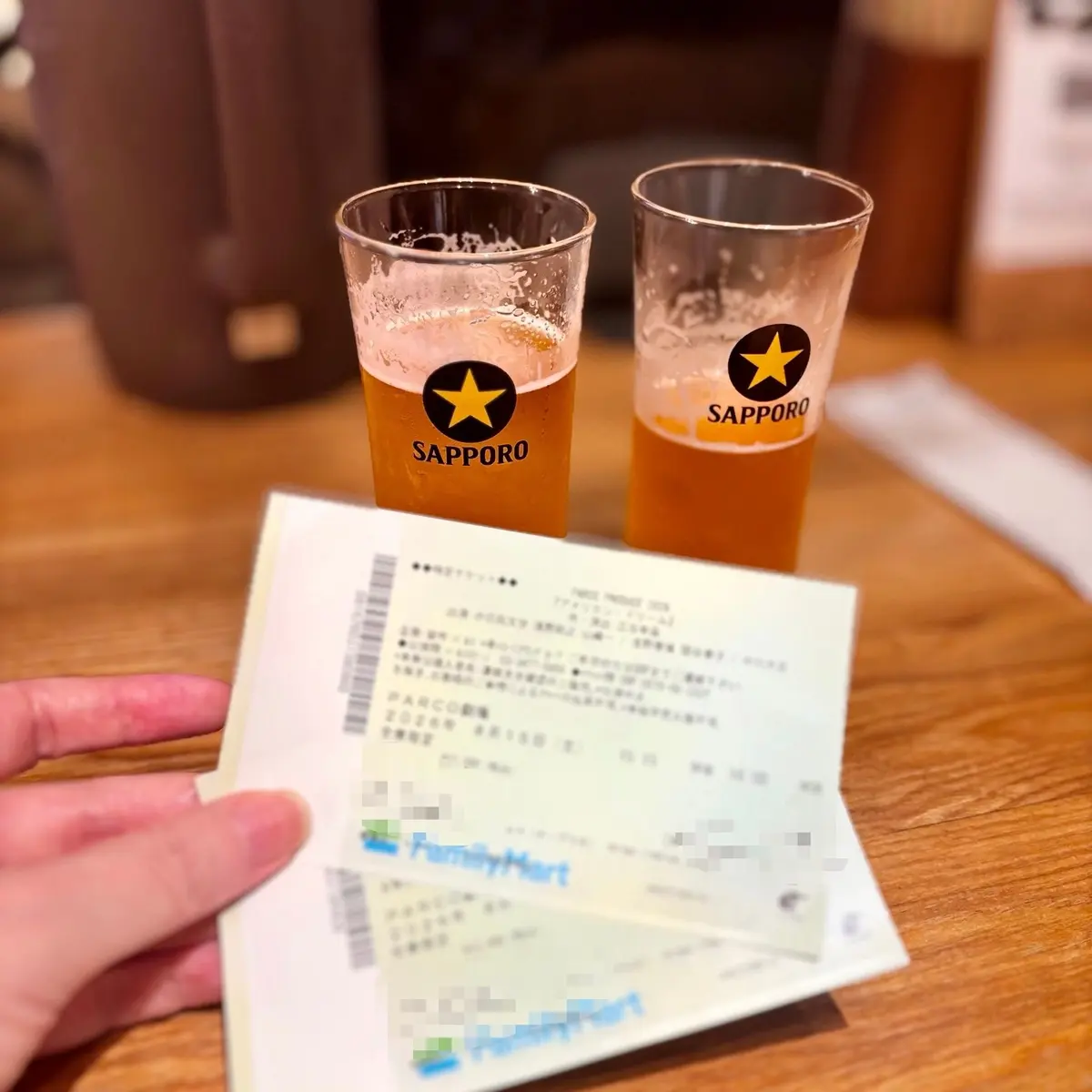木製のテーブルに置かれた、サッポロのロゴが入った2つのグラスに入ったビール。手前にはレシートが置かれている。