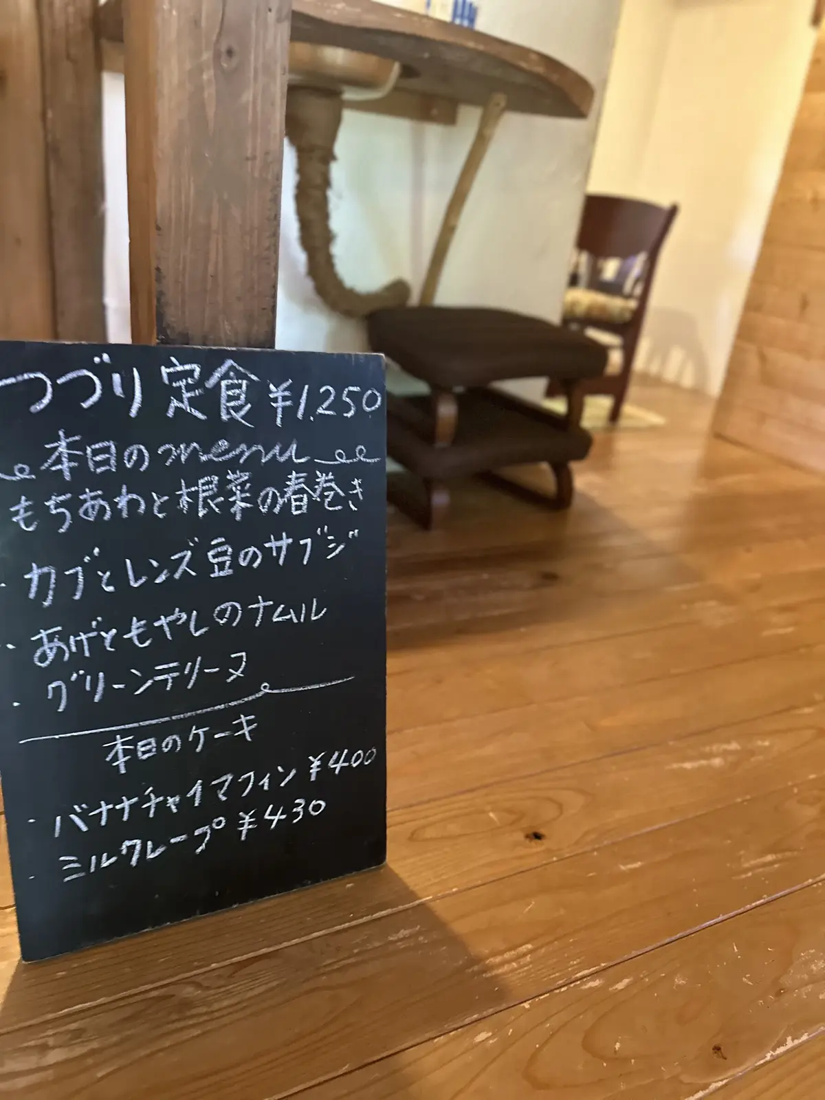 木製のテーブルに置かれた黒板メニュー、価格と品名が手書きで書かれている