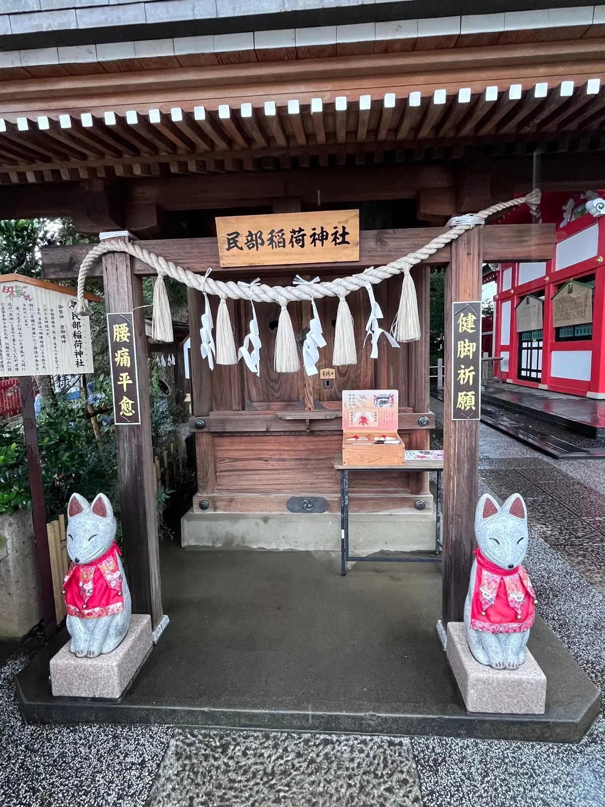木造の神棚に白い狐の像2体、提灯が飾られた神社参道