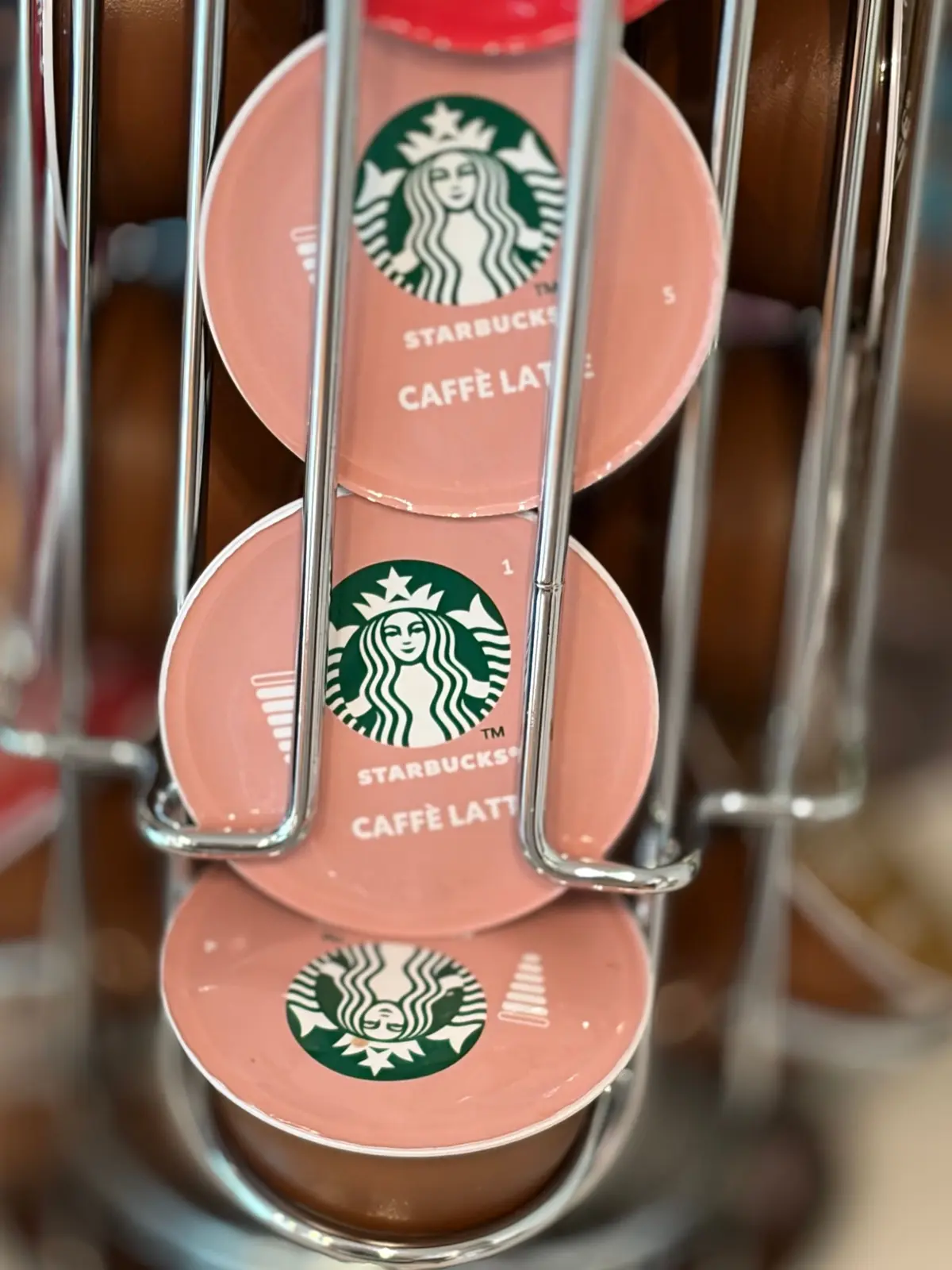 ピンク色のStarbucks（スターバックス）カフェラテのネスプレッソ互換カプセルが、金属製のラックに積み重ねられている。