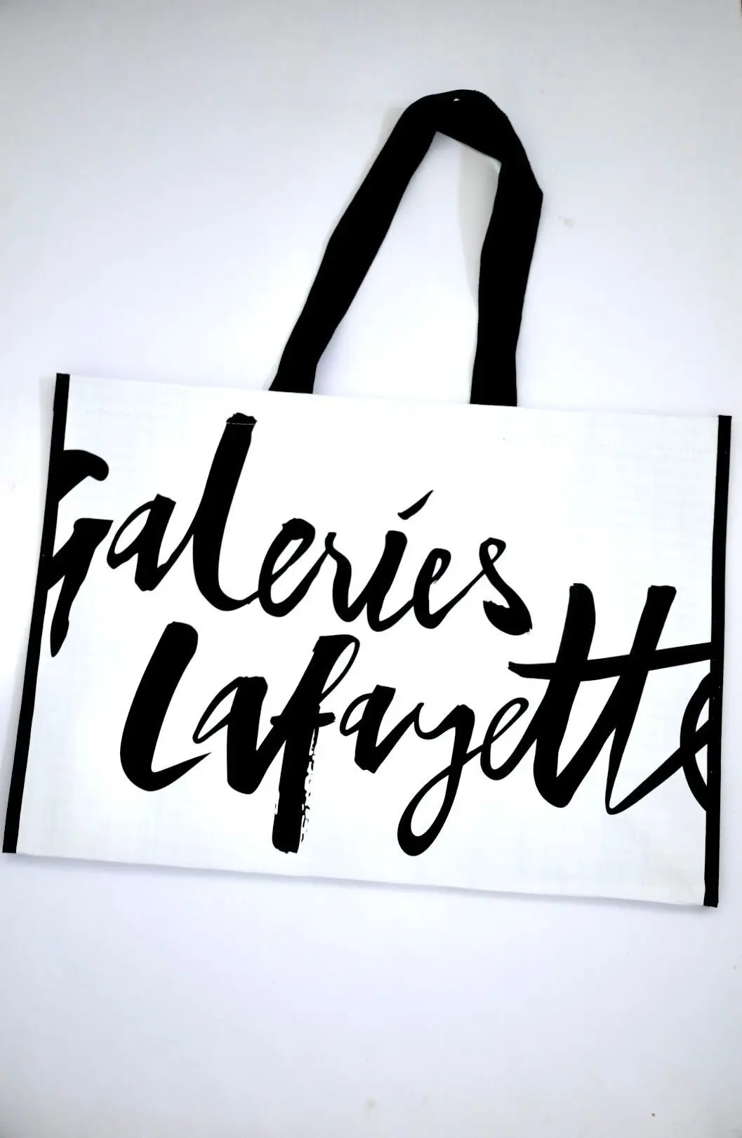 白地に黒の筆記体で「Galeries Lafayette」と書かれたトートバッグ、黒の持ち手がついている