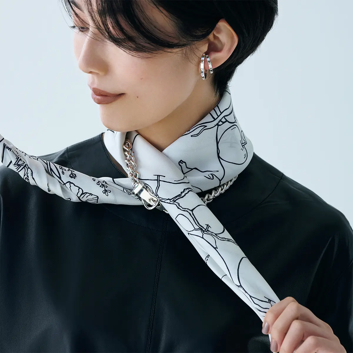 首にかけ、ネックレスに下か ら片側を通し、前で交差する