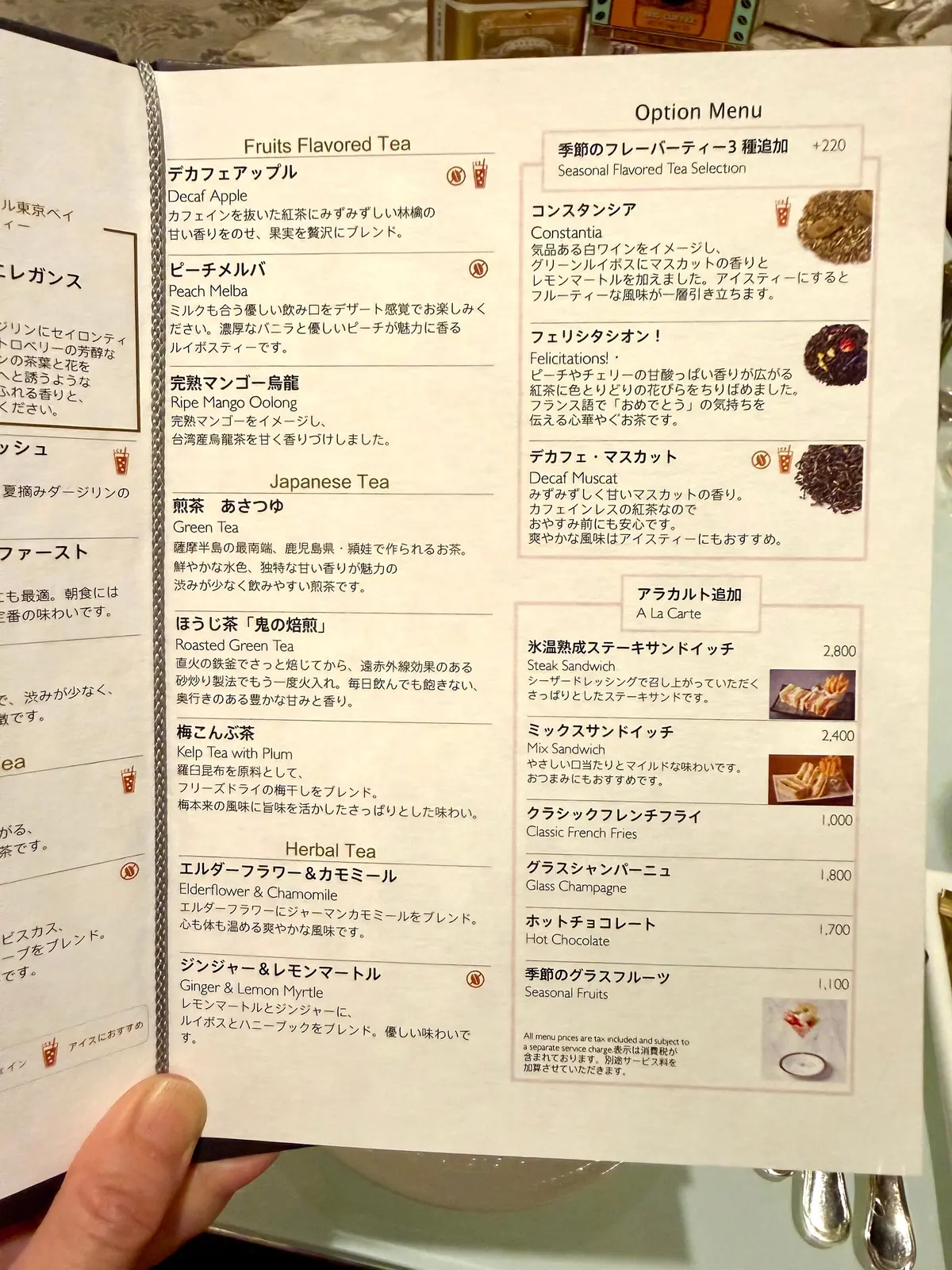 喫茶店「シャンテリー」のメニュー表。左上はフルーツフレーバーの紅茶、中央は季節のフレーバーティー、右側はアラカルトメニュー。紅茶、ケーキ、サンドイッチなどの商品が記載され、価格も示されている。背景はクリーム色で、手書き風のフォントが使われている。
