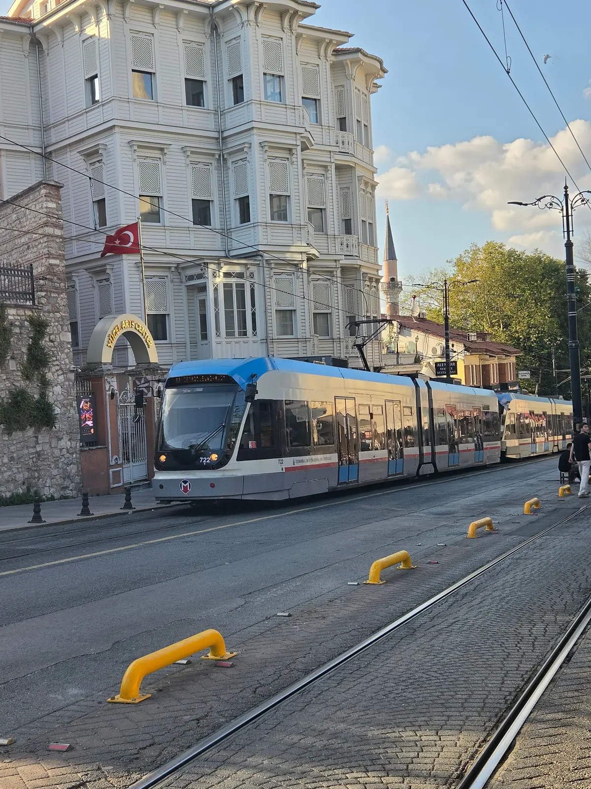 トルコのイスタンブール、アヤソフィア周辺の道路。中央に路面電車線路が走り、歩道には人々が歩いている。背景には建物や緑の木々が見える。