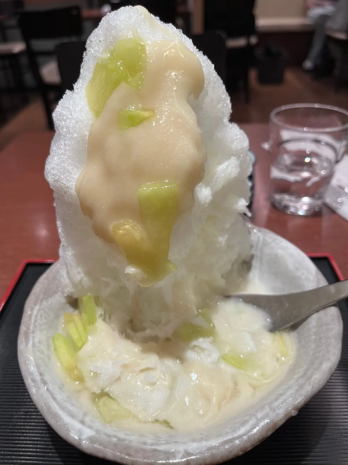 器に盛り付けられたかき氷に、薄切りになった桃がたっぷり乗っている。雪のようにふわふわとしたかき氷と、桃の淡い色合いが目立つ。