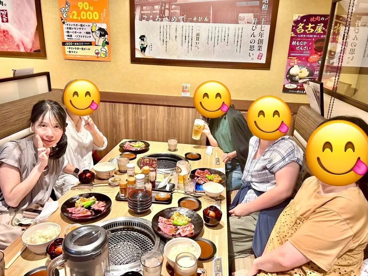 テーブル席に座った複数人が、鉄板焼き料理を楽しんでいる様子。テーブルには複数の鉄板と料理、飲み物があり、賑やかな雰囲気。背景にはメニューなどが掲示されている。