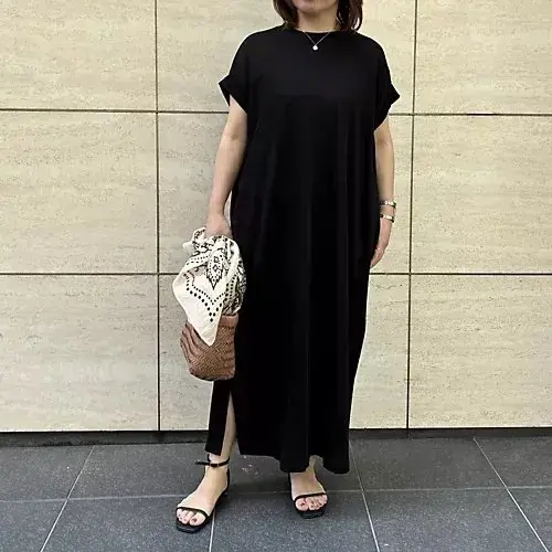 女性が白い傘を差して歩き、茶色の服を着て白いトートバッグを肩にかけた姿