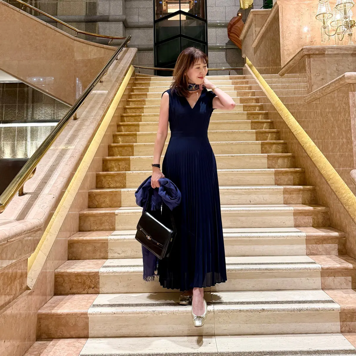 伝統的な木造建築の入口前で、女性が白いカーディガンで手を頭に置いている。右側に「MIKAWAYA HOTEL SULPHATE OF IRON HOT SPRINGS KOWAKIDANI」の看板がある。