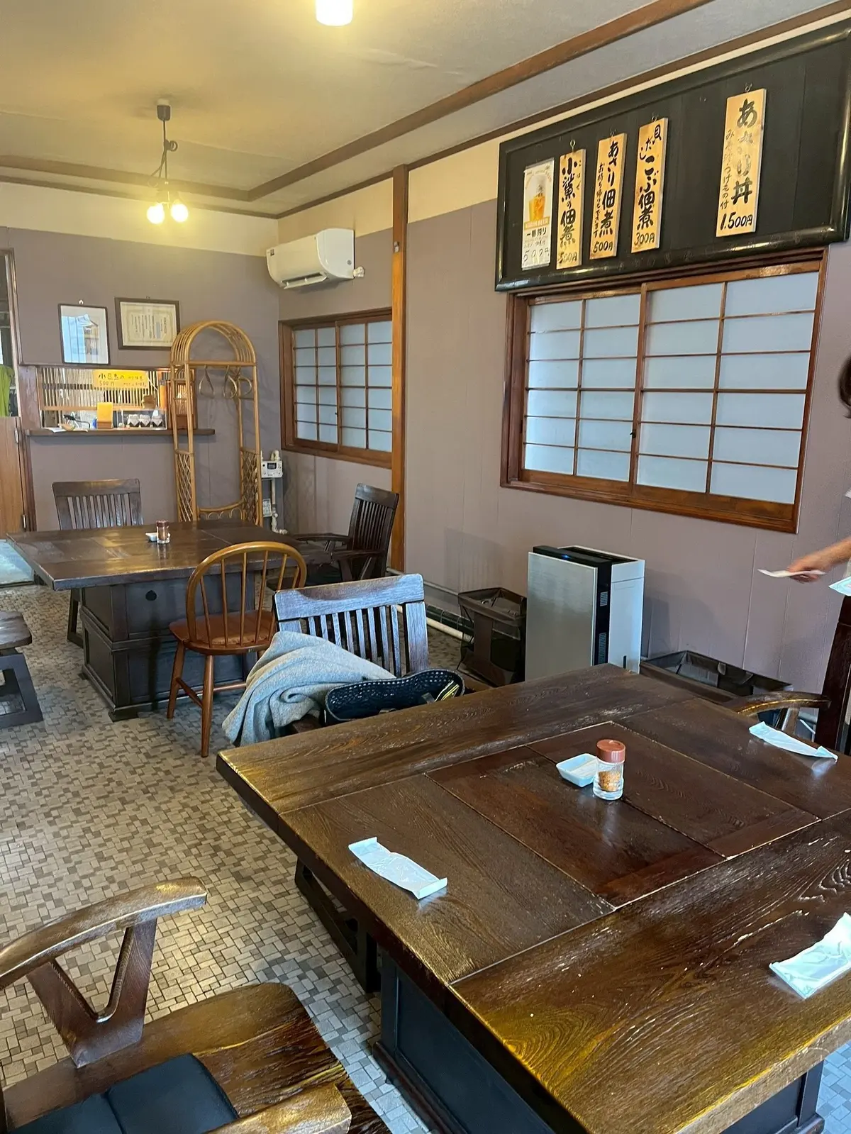 木製のテーブルと椅子が配置された和風の店内、壁には価格表がかけられています