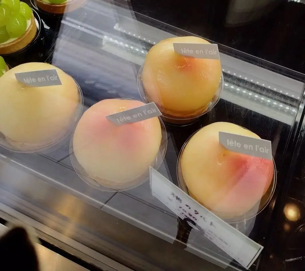 ショーケースに並んだ「tête en l'air」のタルト。緑色のぶどうと、オレンジや桃色のクリームが乗ったものが、透明な容器に入っている。
