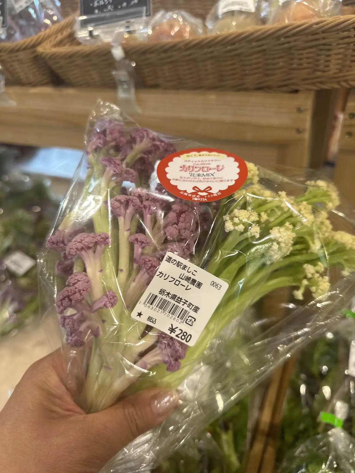 紫と白のカリフラワーのミックスがプラスチック袋に入り、価格ラベルが貼られた状態で店頭に並んでいる
