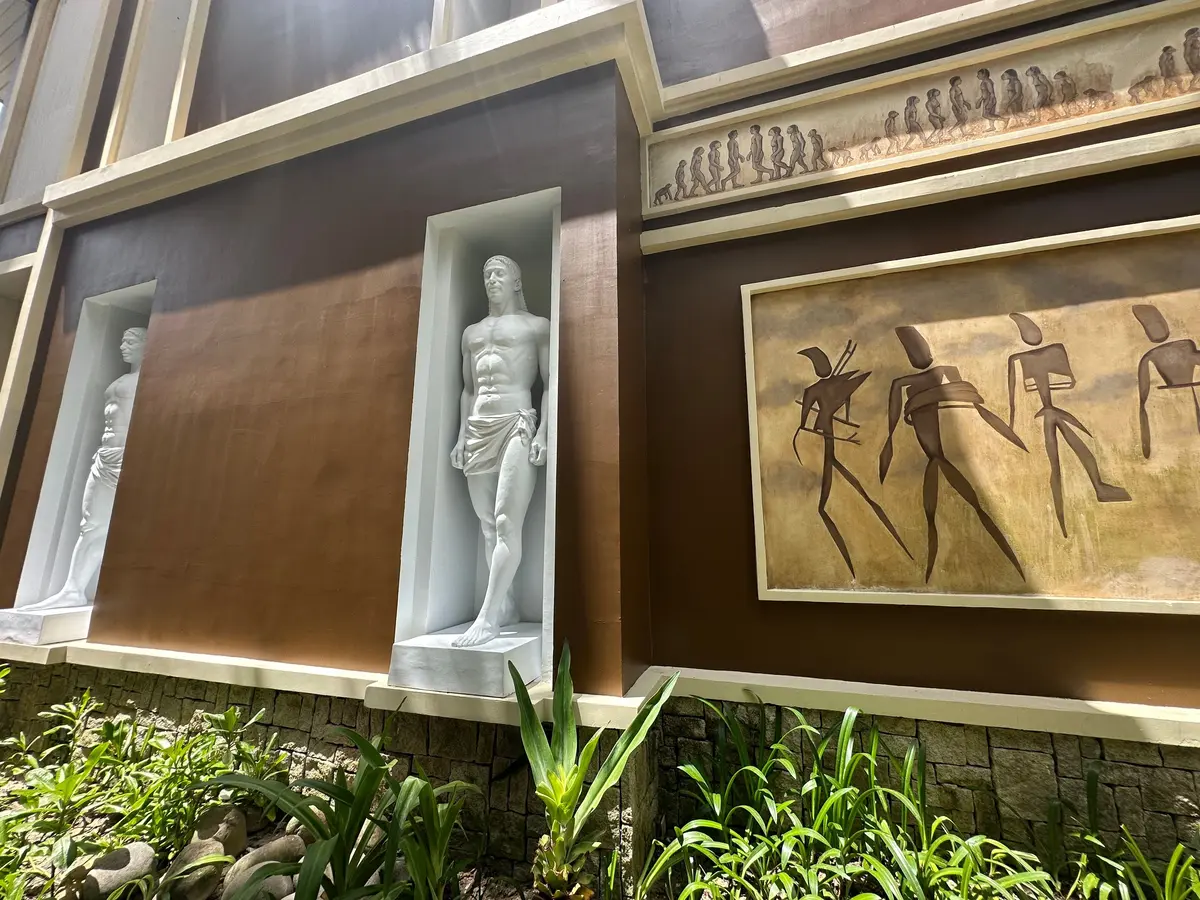 白い箱に収められた男性像と、四人の抽象的な人像が描かれた絵が並ぶ展示物