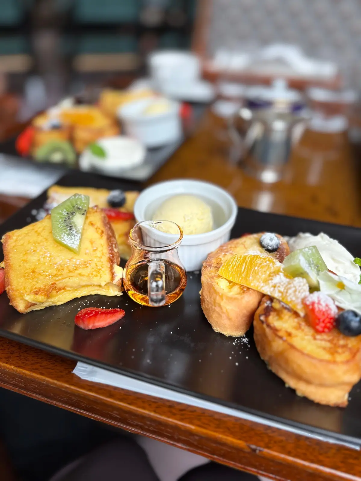パンの上にキウイやベリーをトッピングした朝食プレートと、シナモンシロップ入りの小さなグラスが並んでいる