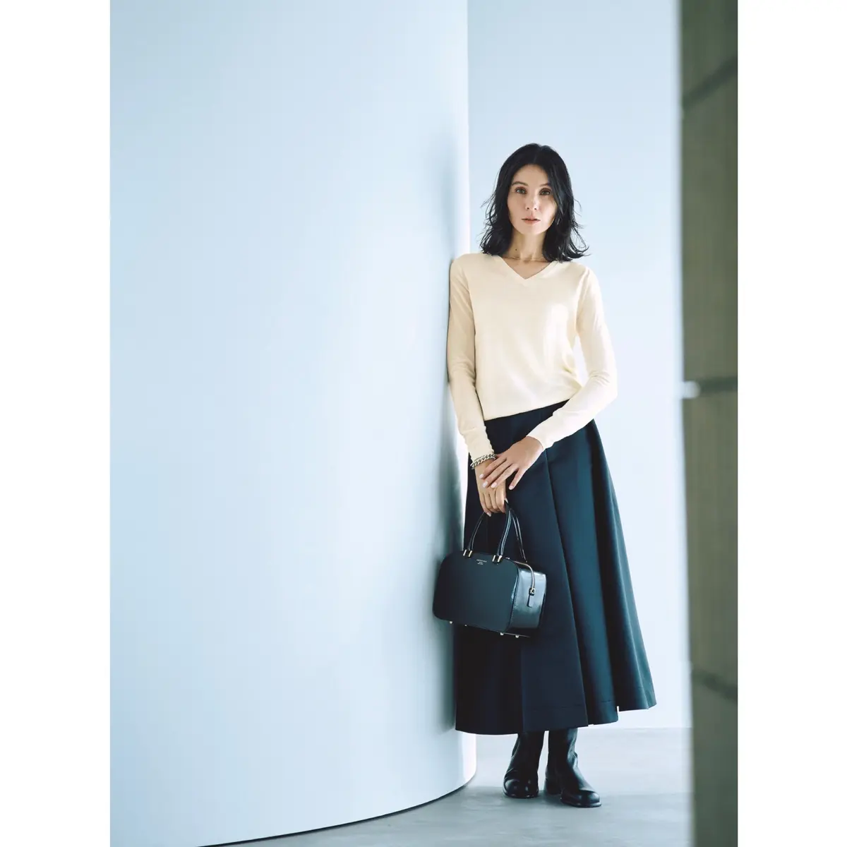 白Vネックニットトップスに黒フレアースカートを合わせたコーディネート　モデル・田沢美亜　