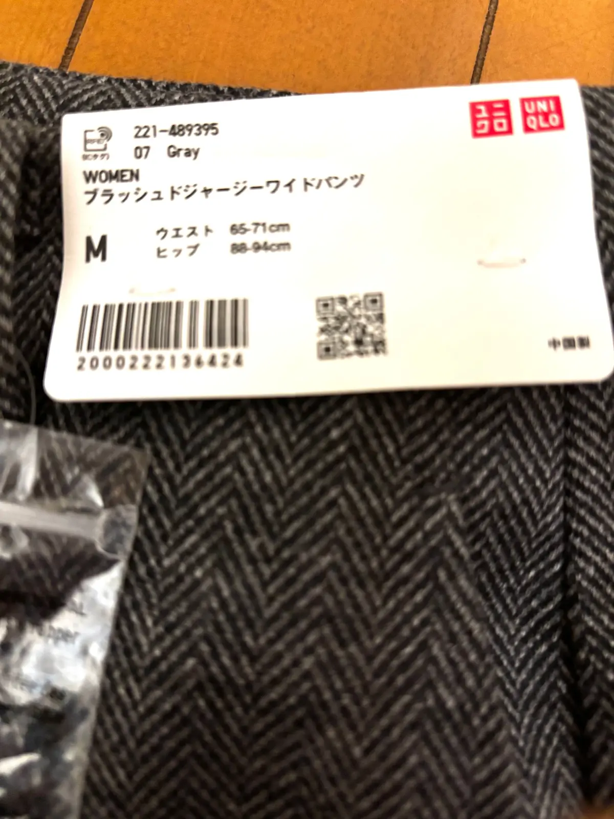 ユニクロの女性用ツイードベスト、グレー、サイズM。胸囲65-71cm、ヒップ86-94cm。バーコードとQRコードがタグに印刷されている。