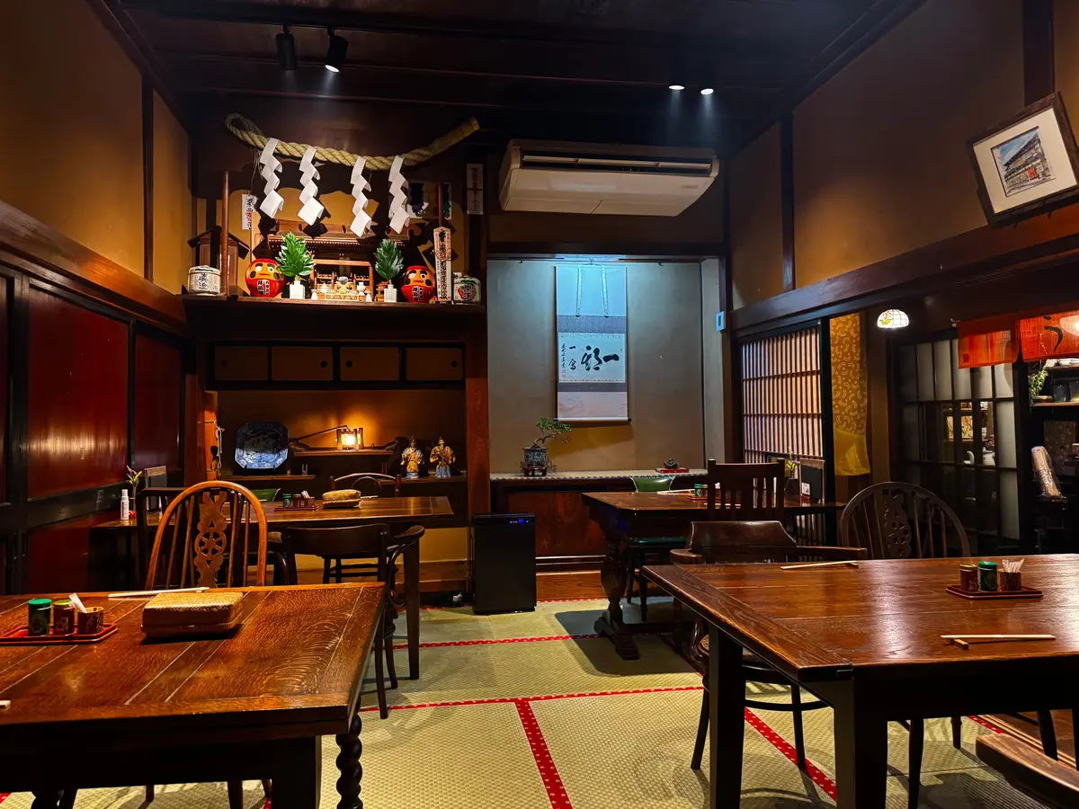 木造の建物に設置された、金文字で「帯富屋」と書かれた看板。左上には「活鰻」の文字、右下には赤い印章がある。