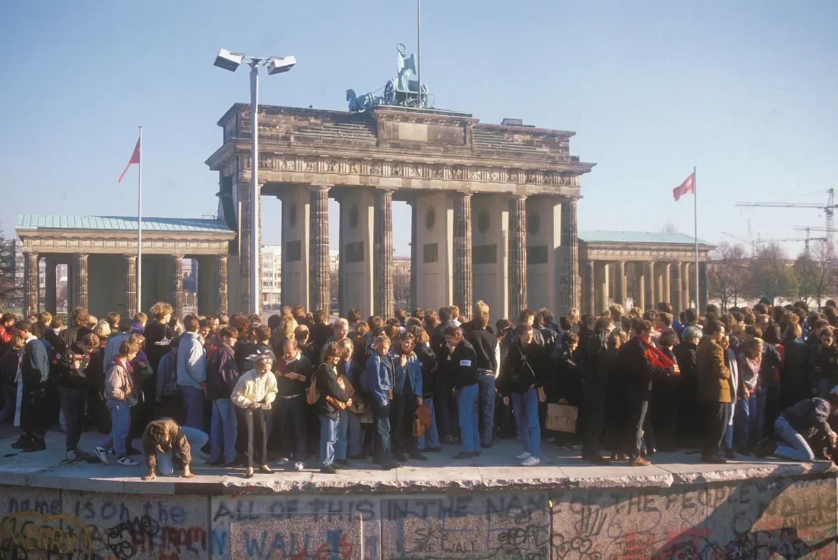 ドイツの変遷を見てきたブランデンブルク門は、1730年代に原型が誕生し、1791年に現在の形となった。 第二次世界大戦後の’61年、門のすぐ西側にベルリンの壁が設けられ、ドイツ分断と東西冷戦を象徴。壁は’89 年11月9日に崩壊した。写真は壁の上で開放を祝うベルリン市民と、それを見守るかのような門