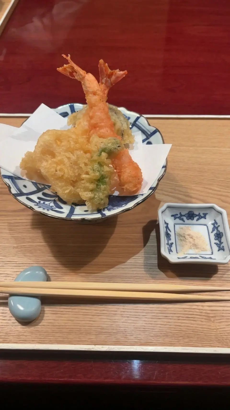 エビと天ぷらが青白の和食器に盛り付けられ、木製のテーブルに置かれている。