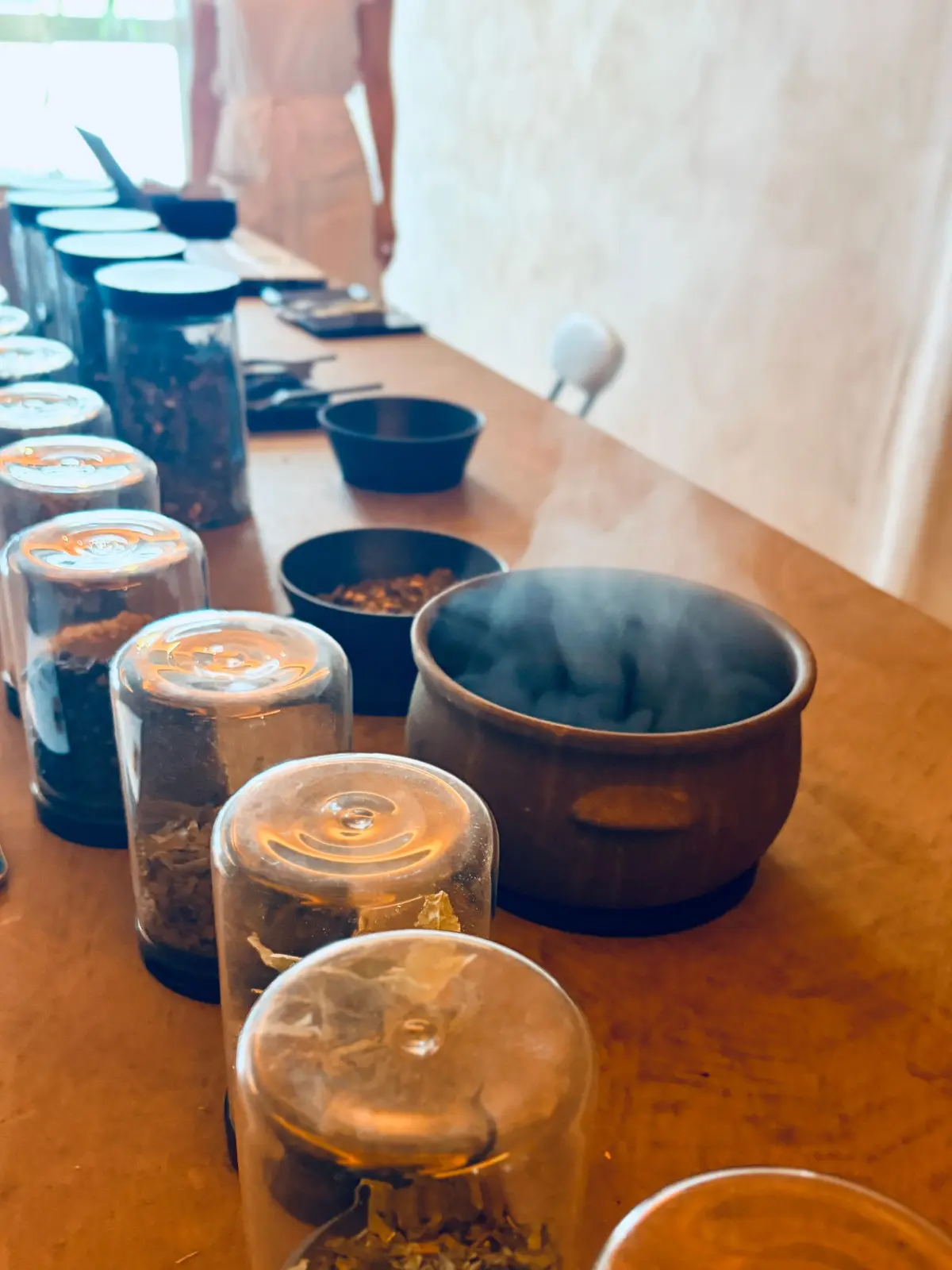 ガラス蓋付きの瓶と蒸し上がった茶碗が並ぶ木のテーブル
