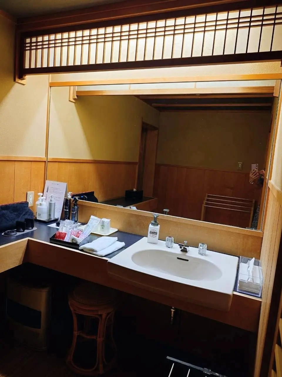九重の洗面台。木製の格子の天井と壁、白い洗面台にタオルやアメニティが並ぶ。