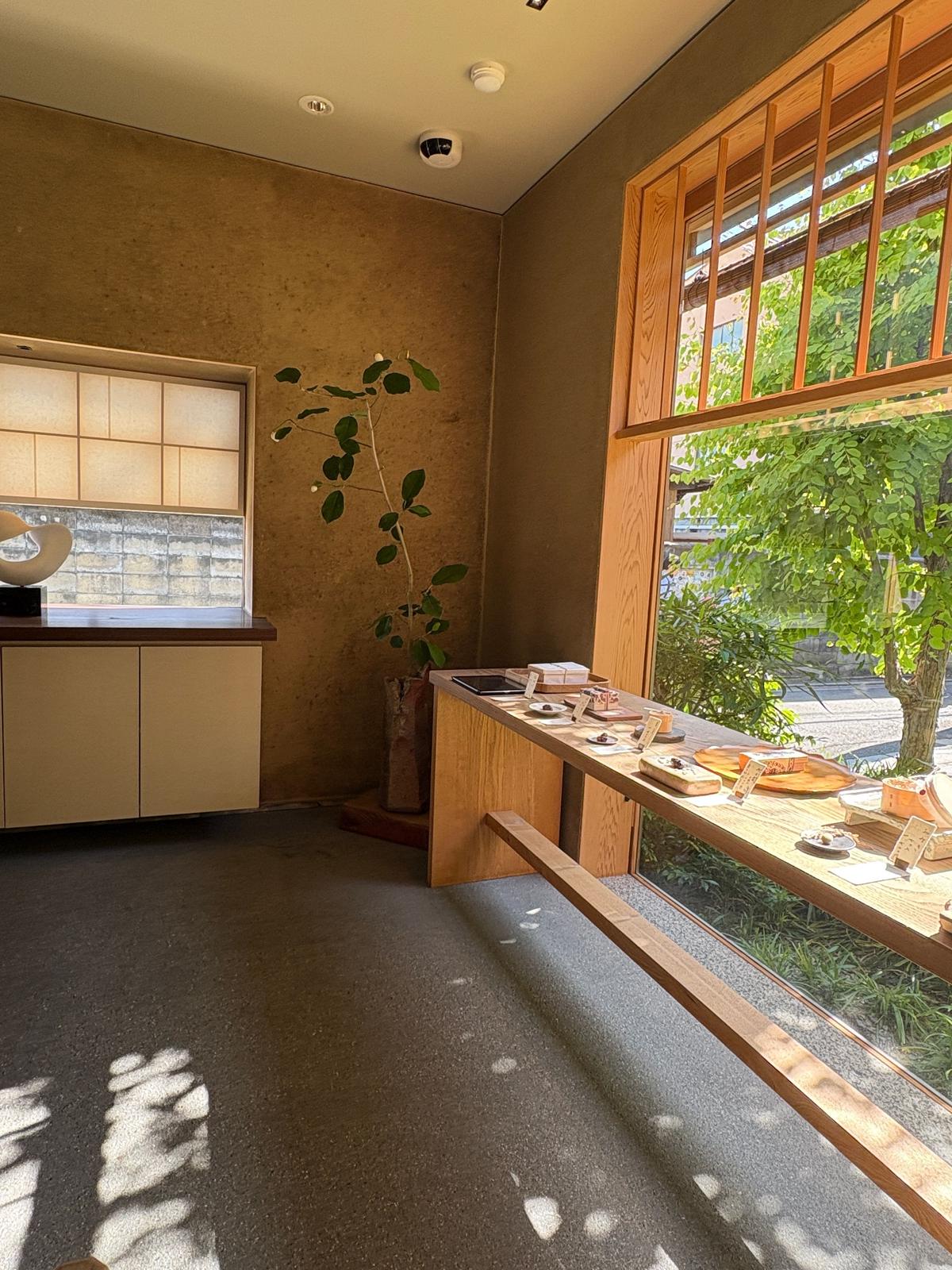 木製カウンターに料理が並び、大きな窓から緑の庭園が望める簡素な部屋