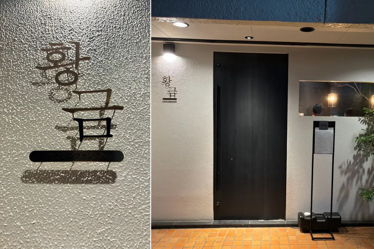 夜の店の入り口。白壁に黒い大きなドアがあり、右には植物が置かれている。韓国料理ファングム。