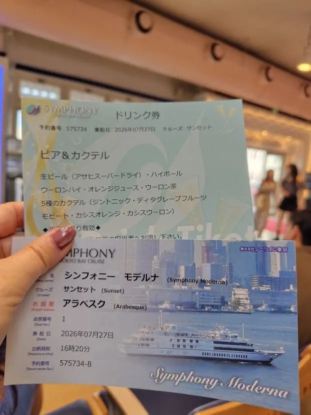 シンフォニーモダン東京ベイクルーズの乗船チケット。緑と黄色のデザインで、クルーズ船と東京の夕景のイラストが中央に配置。乗船日、時間、予約番号などの情報が記載。