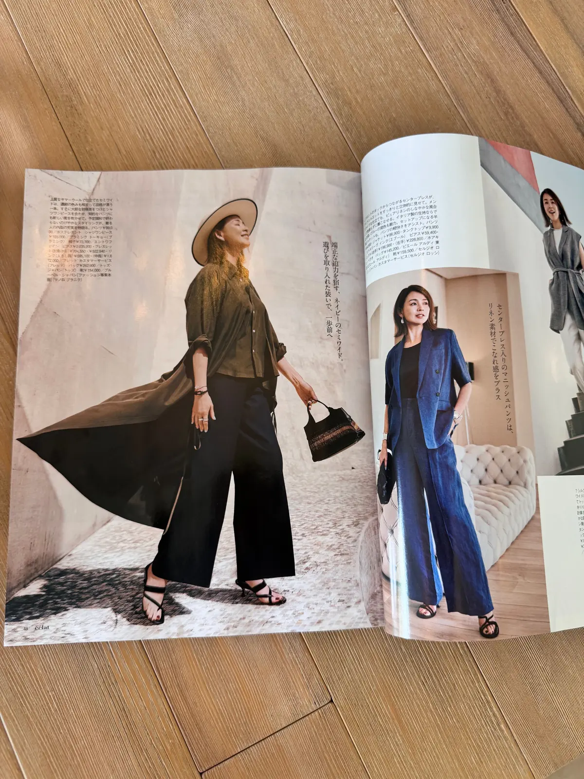 雑誌のページに掲載されたファッション写真。左は、ベージュのシャツと黒のパンツにグレーのロングコートを羽織った女性が歩いている様子。右は、ネイビーのシャツとパンツに白のトップスを合わせた女性が立っている。背景には、木目調の壁と家具が見える。