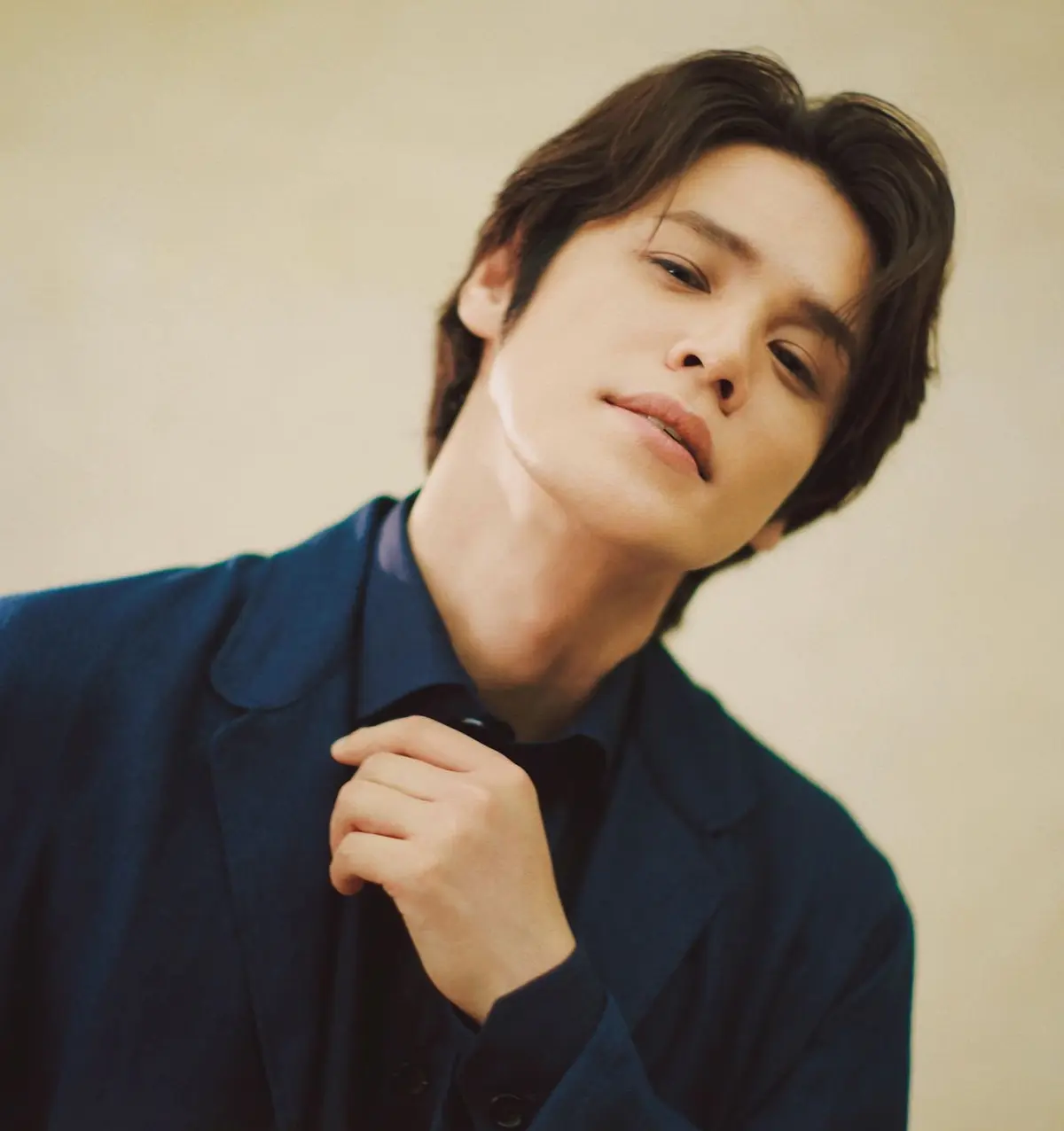 【宮野真守さんインタビュー＜後編＞】　役者としての自分を呼び覚ましてくれた「劇団☆新感線」の舞台の魅力　若者が淡い背景に寄りかかり、ほほ笑む。紺色のスーツを着て、左手で蝶ネクタイを調節している。