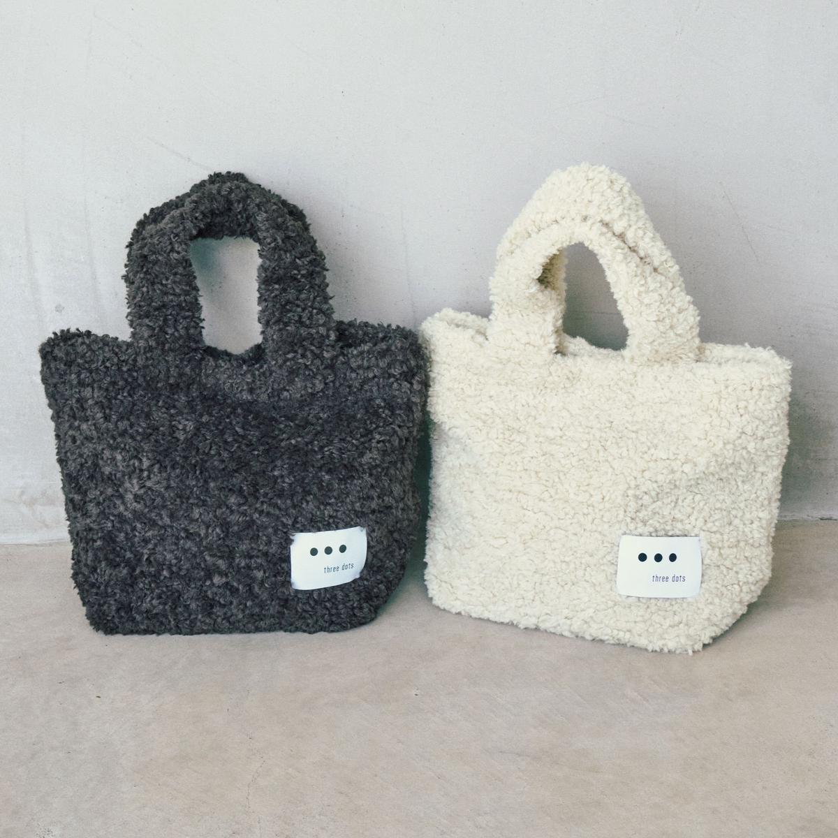 左がグレー、右がアイボリーの、テクスチャード加工されたふわふわのトートバッグ。それぞれに「three dots」のロゴが入った白いタグが付いている。