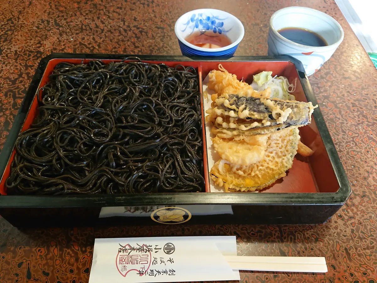 赤いトレイに黒いワカメと揚げ物が入り、青い花模様の小鉢と白いカップが置かれている