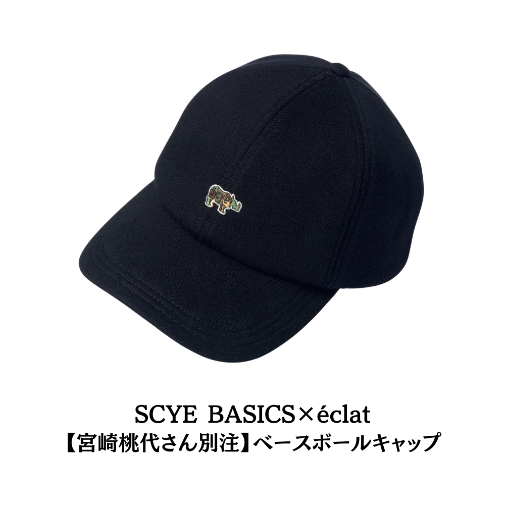 黒色のベースボールキャップ。前面中央に、緑と青のワニの刺繍ロゴが白枠で配置されている。SCYEとéclatのコラボレーション商品。