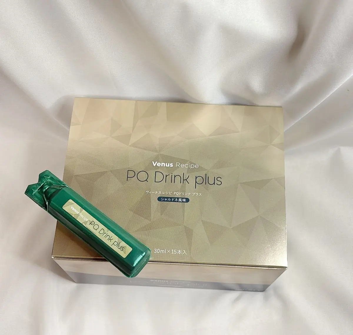 Venus Recipe PQ Drink plusの箱と1本。箱は白地に幾何学模様、PQ Drink plusの文字が黒で印刷。1本は緑色のスティックタイプ。箱には「30ml x 15本入」の記載あり。