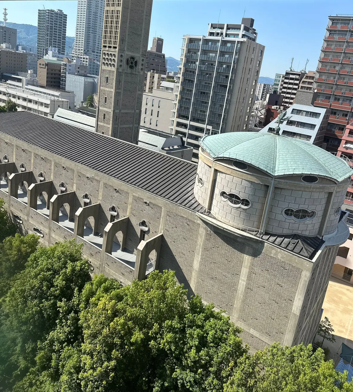 円形のドーム屋根を持つコンクリート造りの建物と、周囲の高層ビルが広がる都市景観