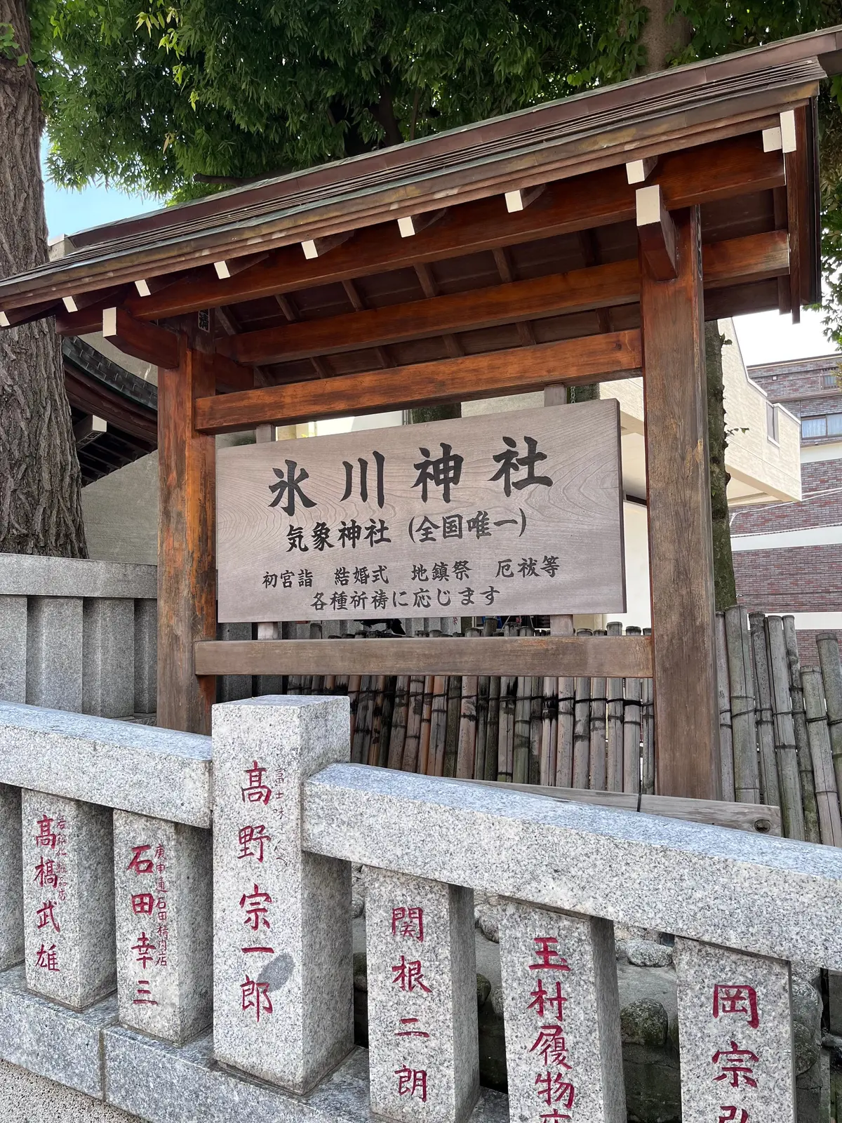 木造の庇の下に設置された、霜川神社と書かれた看板。石段の前に、赤い文字で名前が刻まれた石碑が並ぶ。