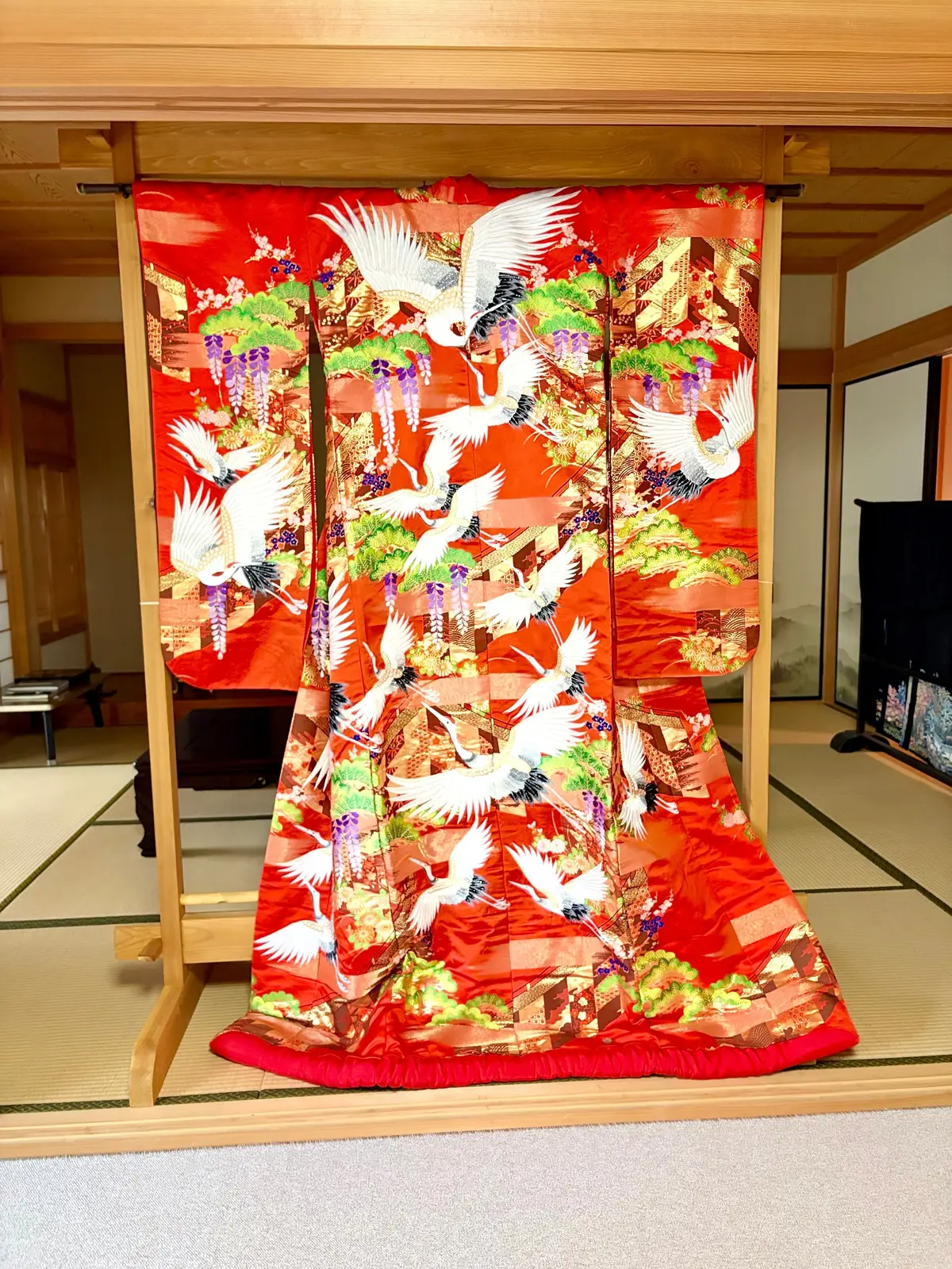 赤い着物に白い鶴と緑の草木が描かれた伝統的な日本風の部屋