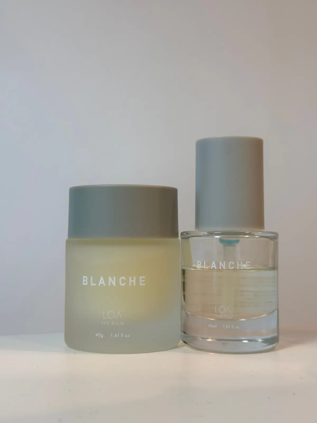 LOAのBlancheというブランドの化粧品2点。左は淡い黄色のバーム、右は透明なオイル。それぞれ、グレーのキャップが付いている。