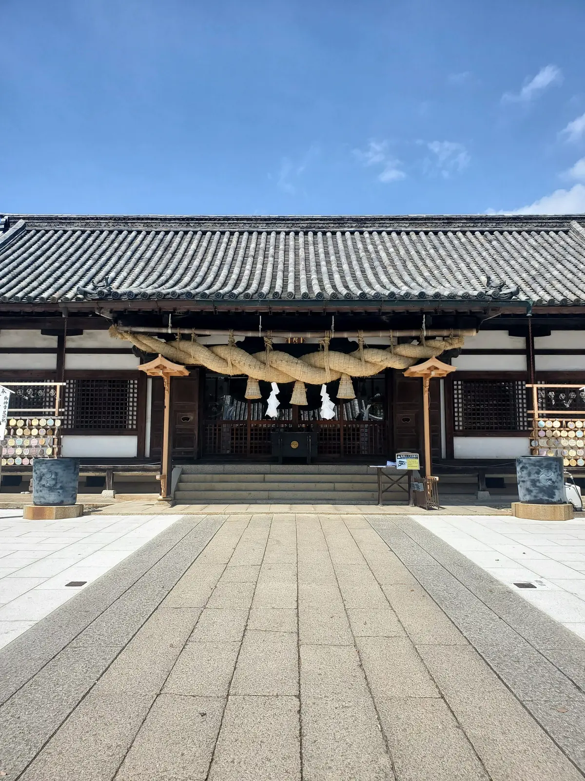 屋根が特徴的な伝統的な日本の寺院。正面には石畳の道が続いており、屋根の上には装飾的な龍の彫刻がある。青空を背景に、落ち着いた色調の建物が静かに佇んでいる。