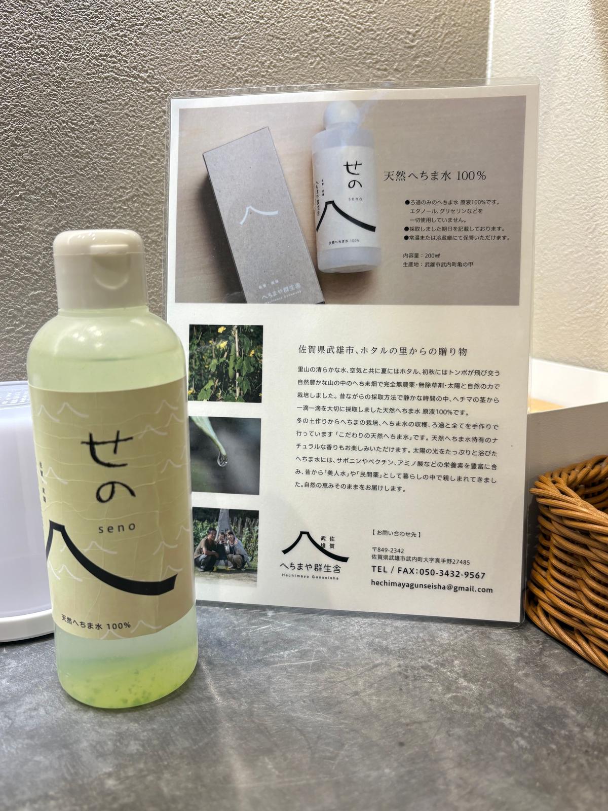 「せの」のボトルとパンフレットが並ぶ。ボトルは淡い緑色で、ラベルに「天使の水100%」と記載。パンフレットにはボトルの写真と説明文、自然の風景画像、連絡先情報が含まれる。