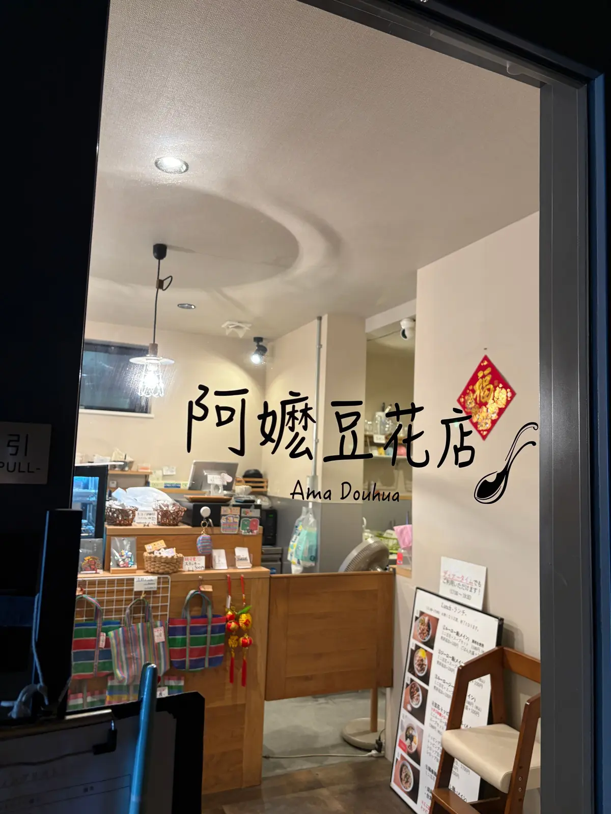 店内の明るいカフェ、木製カウンターと棚、メニュー表、装飾品が並ぶ