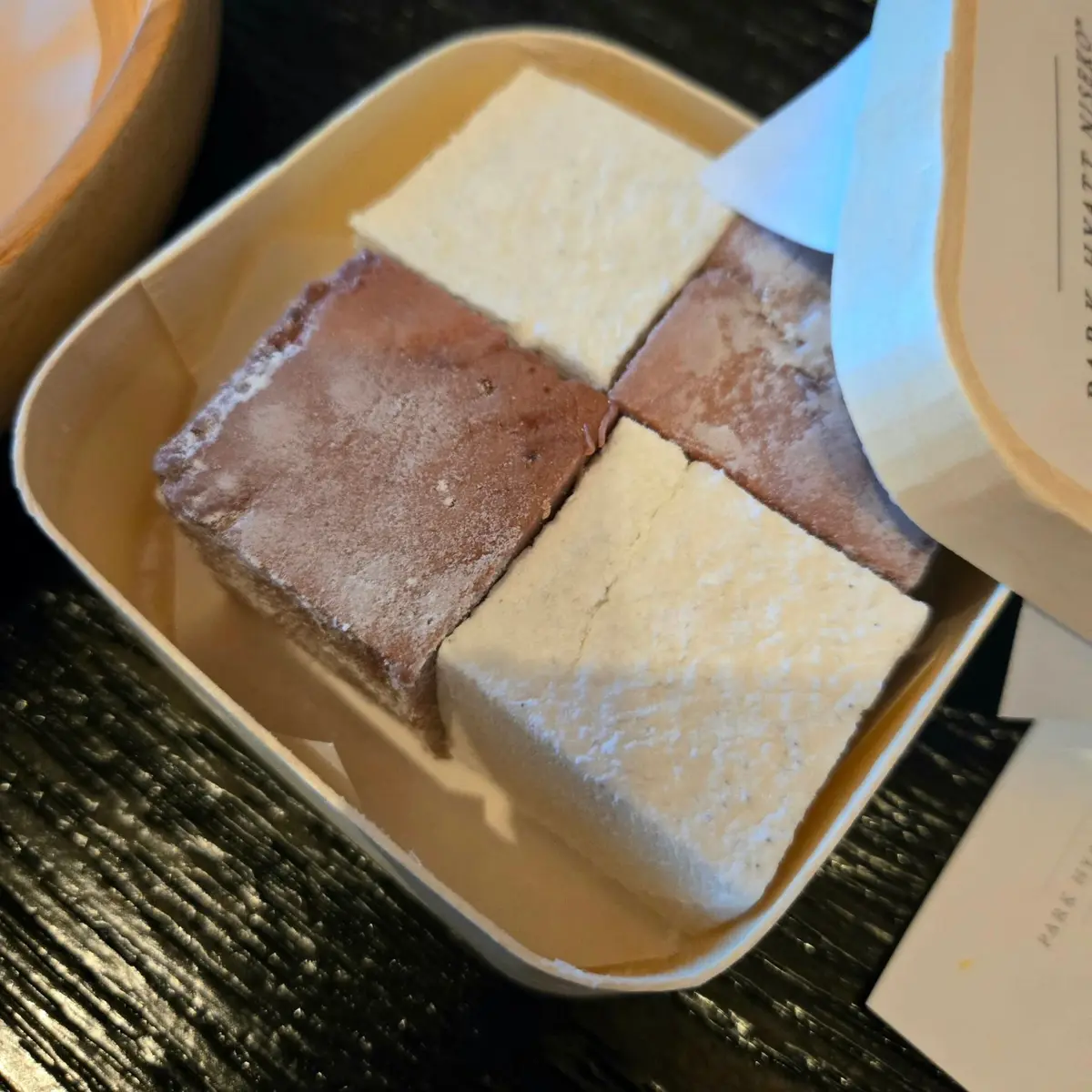 朴木本舗の四角い生菓子詰め合わせ。白、淡いピンク、濃いピンクの3色で、それぞれ異なる模様が施されている。木製の箱に入っており、上品な印象。