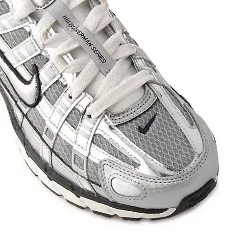 銀色のメタリック素材を使用したNike（ナイキ）のシュー。白いシューレース、黒いソール。側面に黒のロゴマークが配置されている。